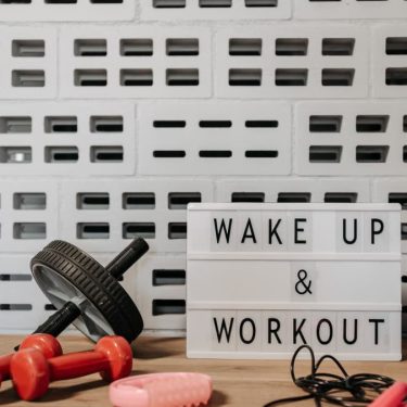 Fitness gear and motivational sign in home gym setup against a brick wall.